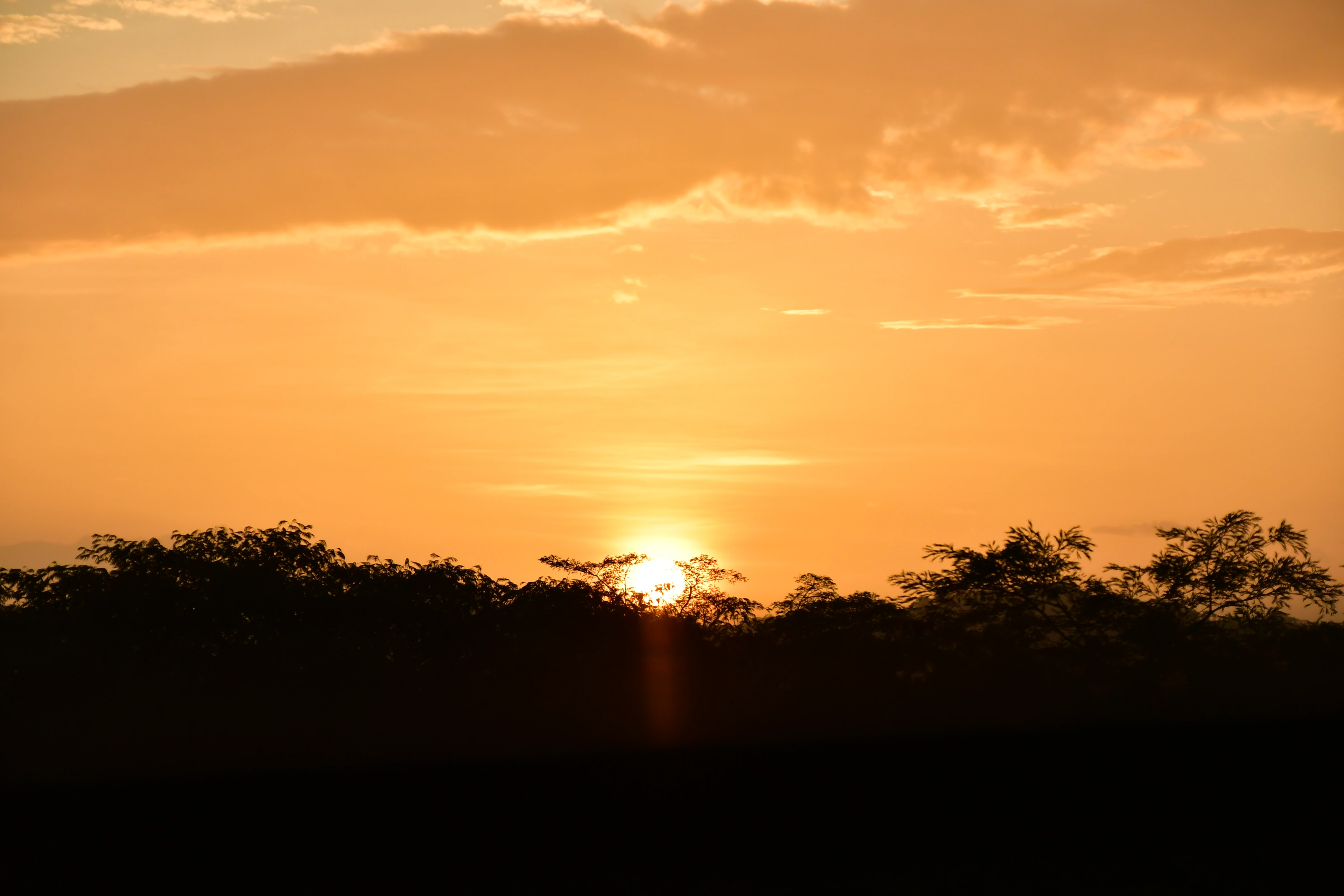 Guest flying a zipline against an orange sunset sky over the Guanacaste hills