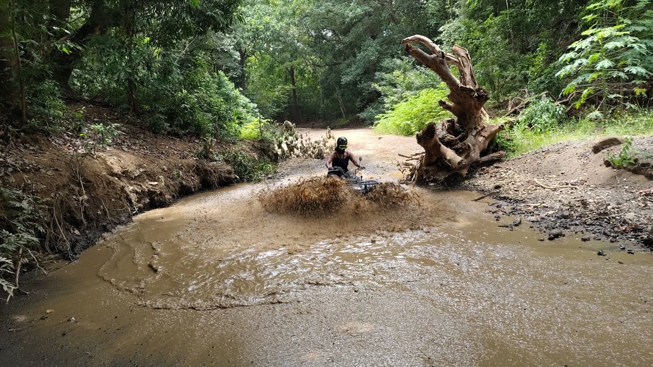 ATV splashing through a muddy river crossing