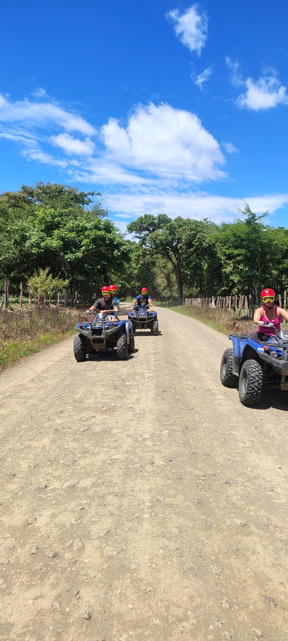 Four ATVs on a country road under a blue sky